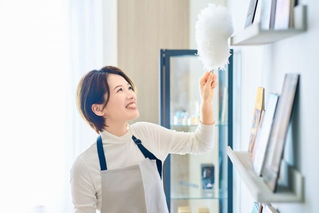 部屋の隅々の埃を掃除する女性