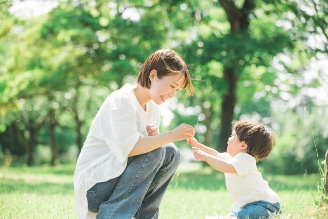 新緑の中で遊ぶ男の子と母親