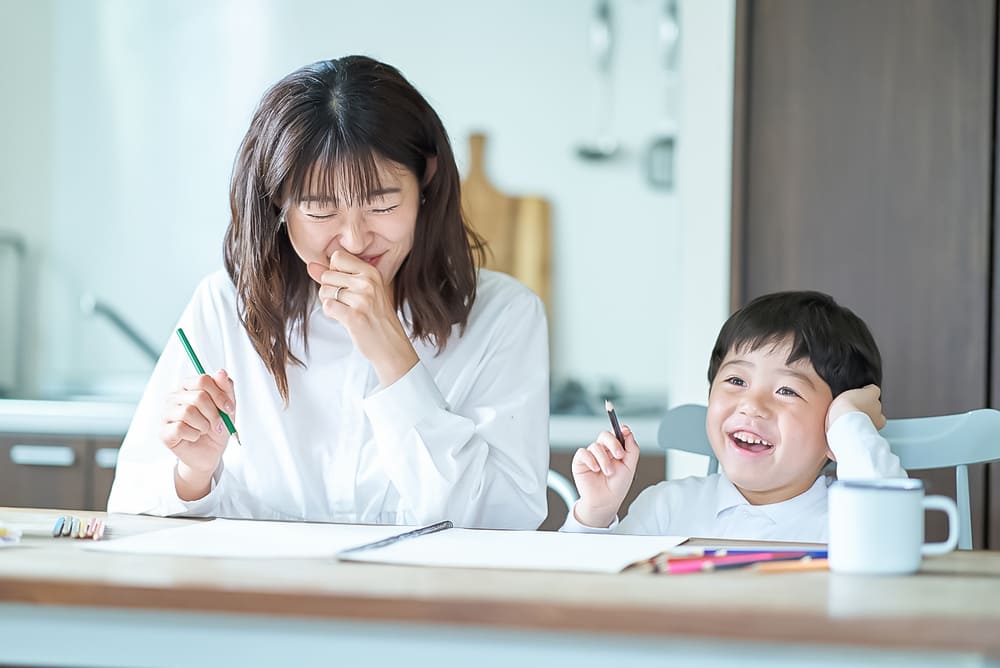 部屋で鉛筆とノートを使って勉強する親子